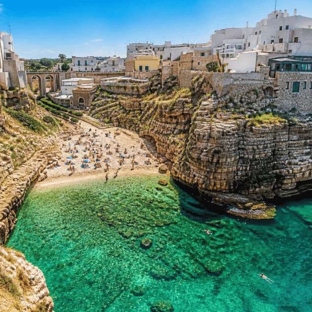 Lama Monachile cove and beach in Polignano a Mare framed by limestone cliffs and whitewashed houses.